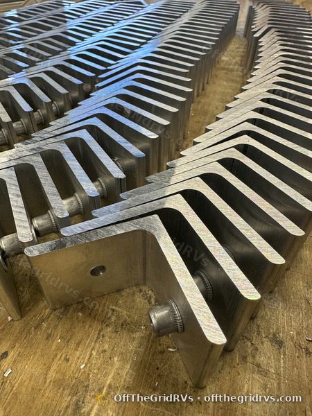 Close-up of a batch of finished machined aluminum tilt brackets with press-in threaded inserts installed